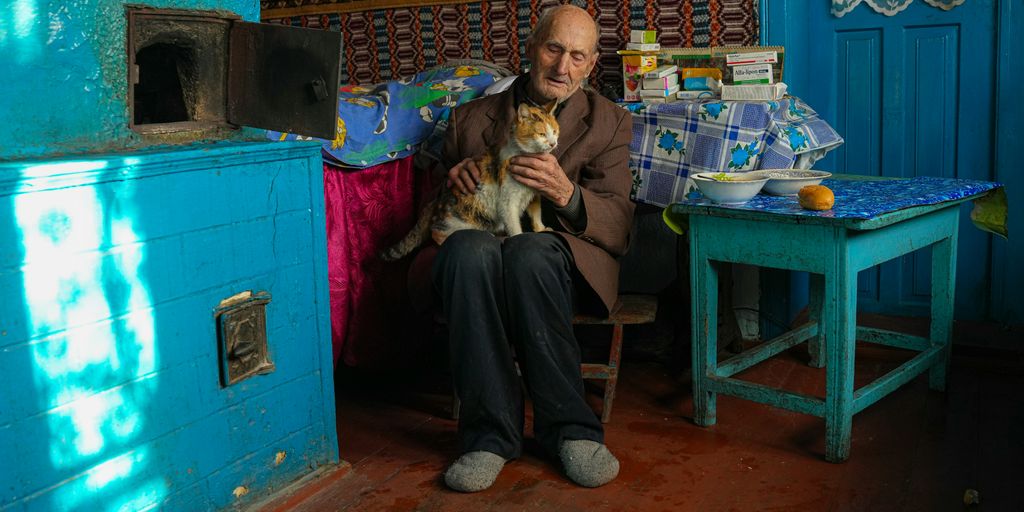 a man sitting on a chair holding a cat