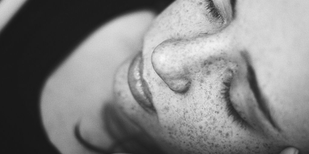 grayscale photo of woman's face with freckles