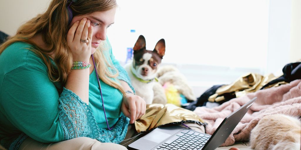 woman in teal long sleeve shirt holding black laptop computer
