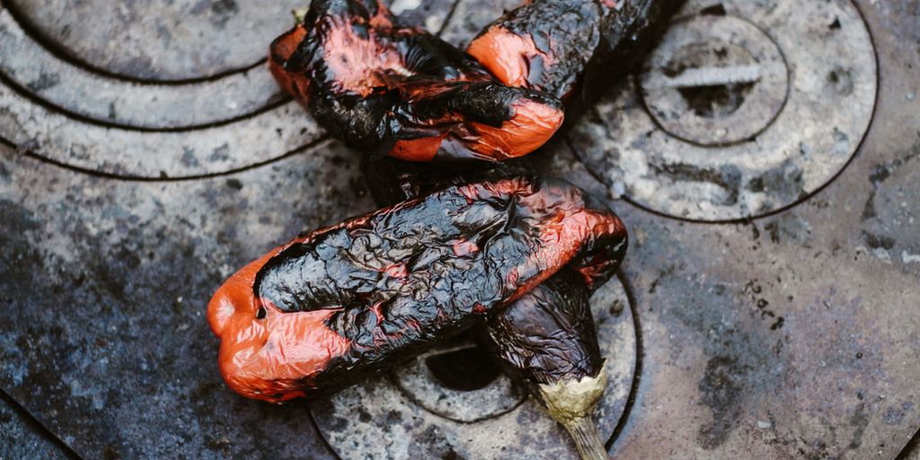 two orange-and-black cooked eggplants on gray stove