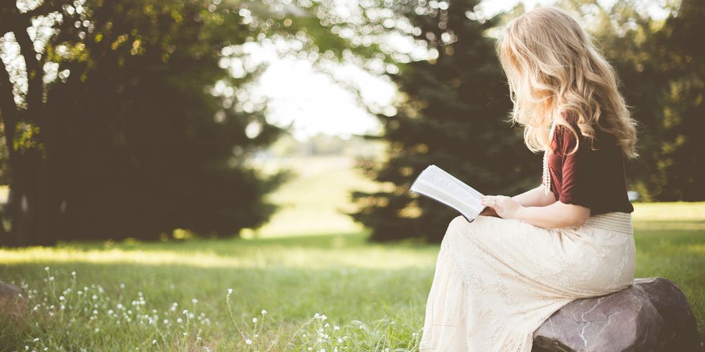 woman sitting while reading book