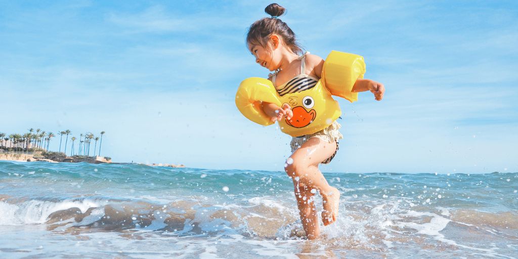 girl playing beside body of water during daytime