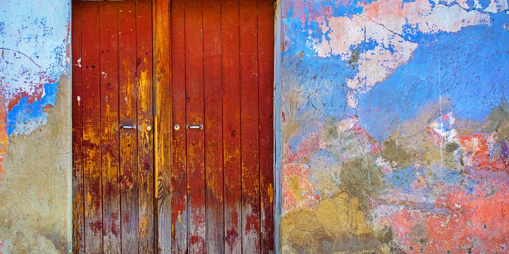 red wooden door of blue, red, and brown painted wall