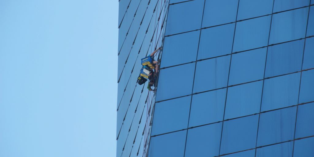 man in yellow jacket and black pants standing on top of building