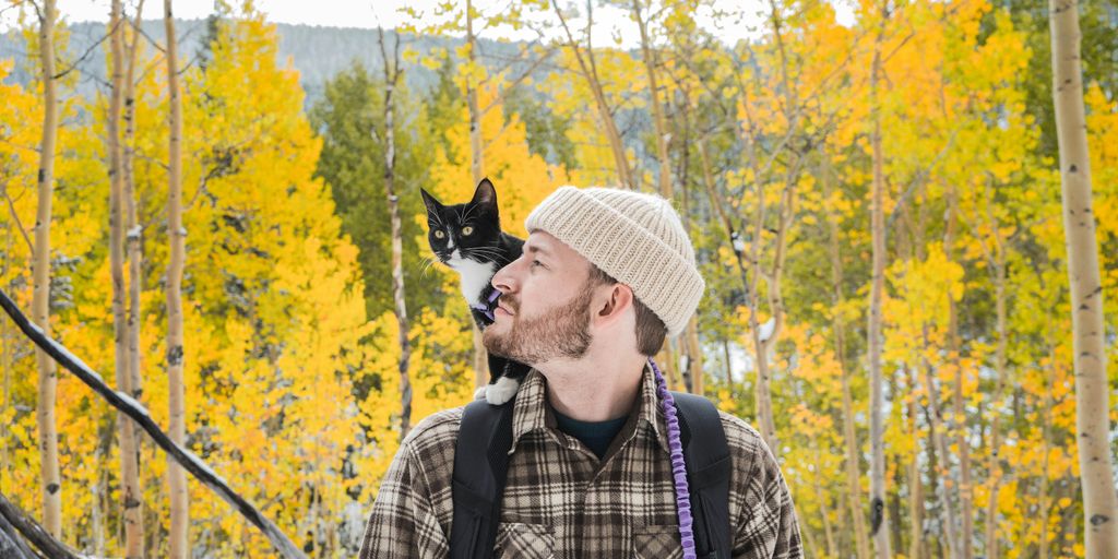 man in white hat and plaid shirt with black and white cat on his head