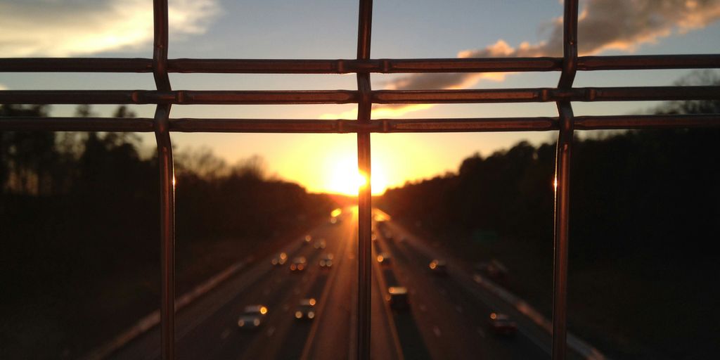 vehicles on highway between silhouette of trees