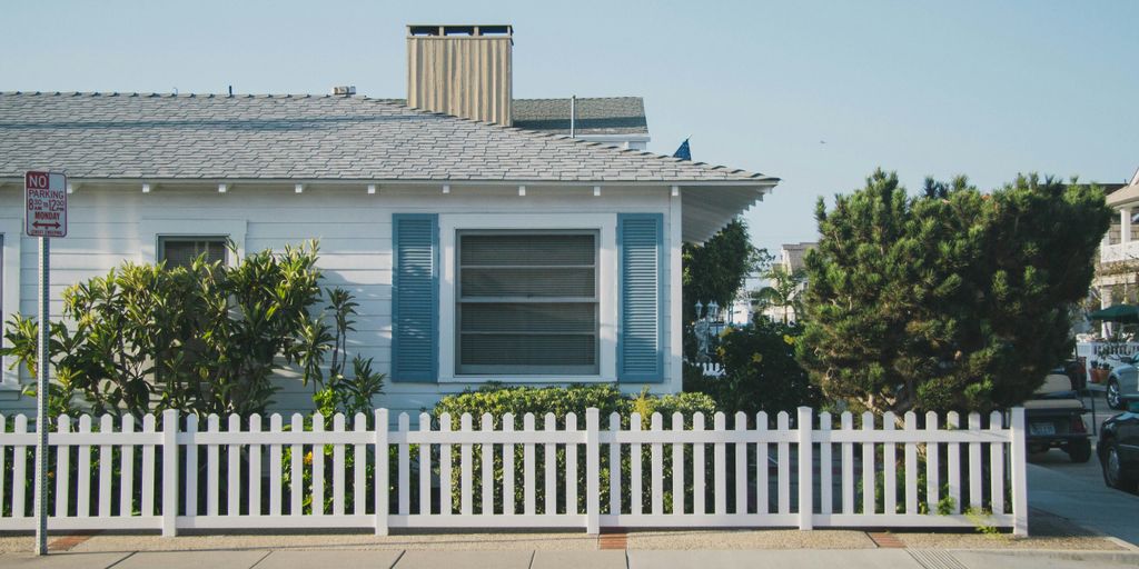 white and blue house beside fence